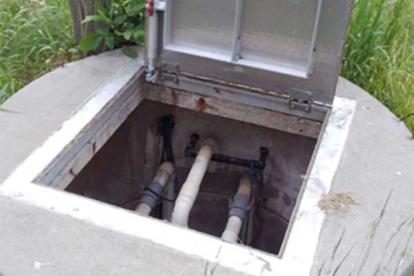 opened underground utility box exposing pipes